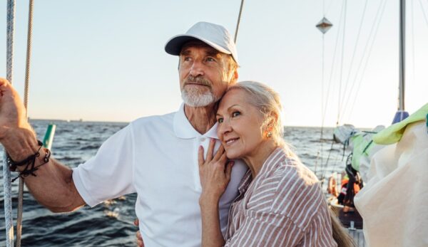Retired couple standing together on sailboat.