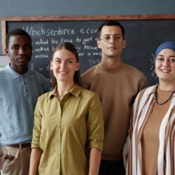 Group of English Language Instructor and Students Smiling at Camera in School Classroom