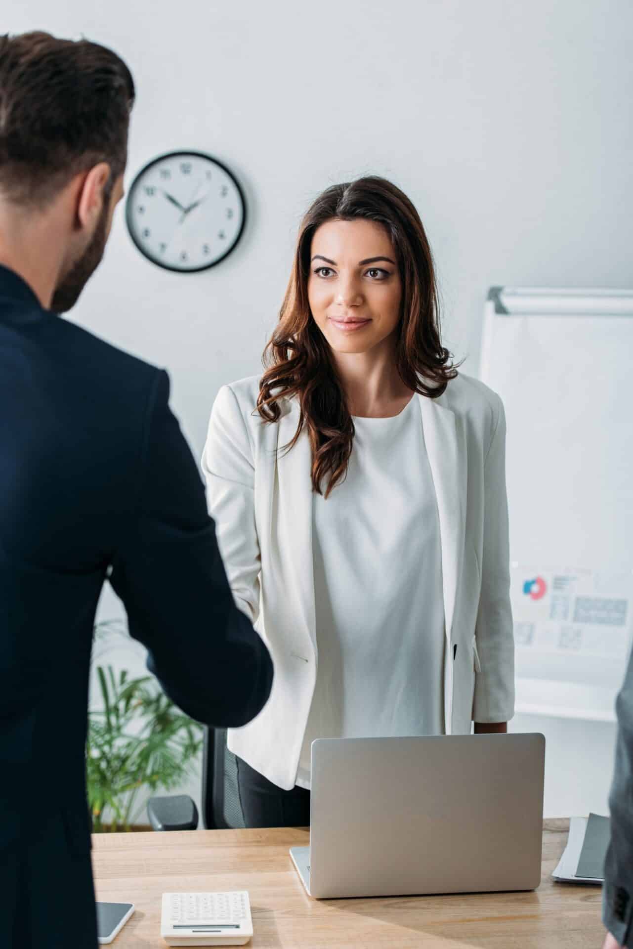 selective focus of advisor shaking hands with investor at workplace