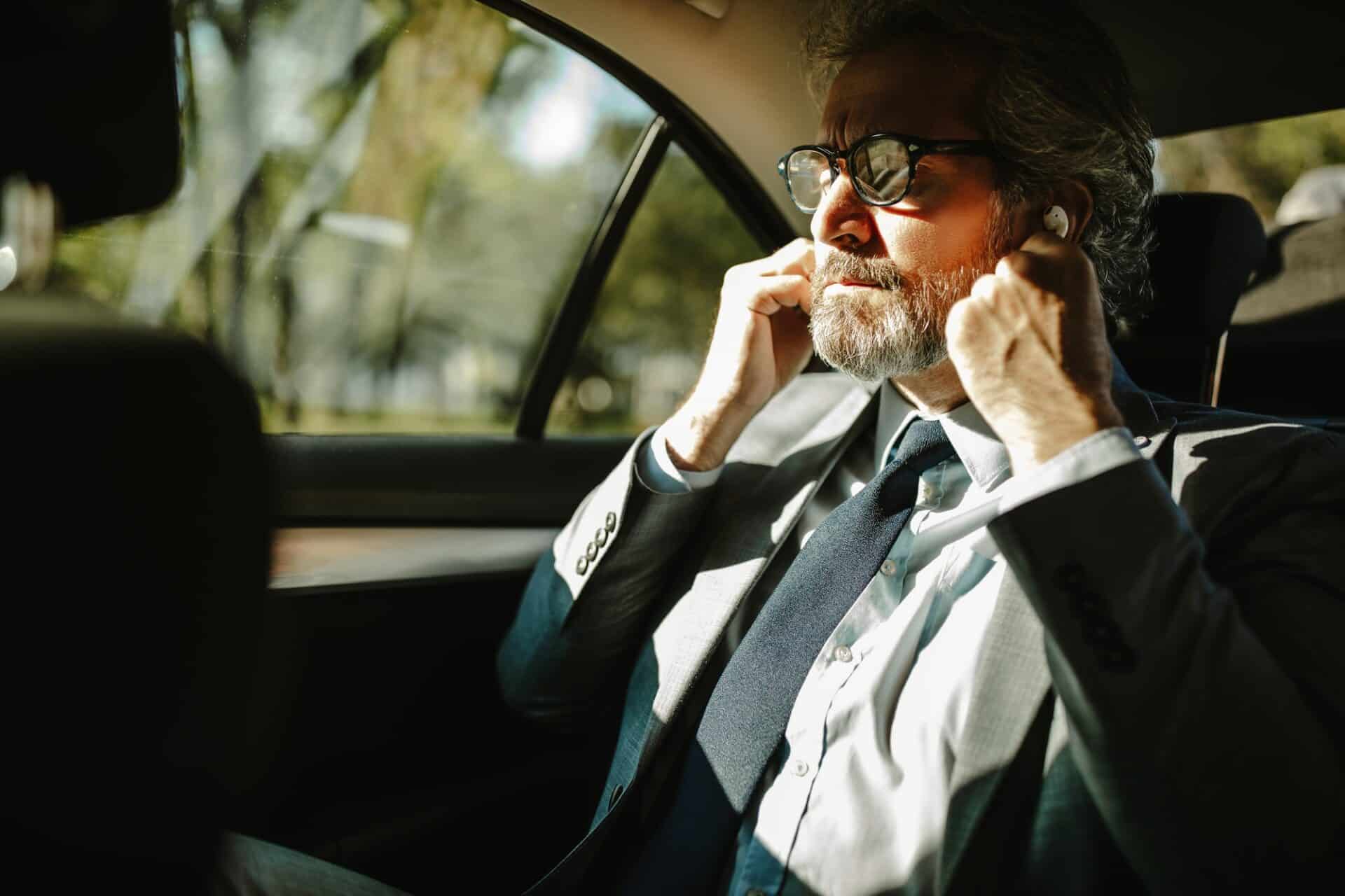 An older businessman putting on headphones prepares for a conference call.