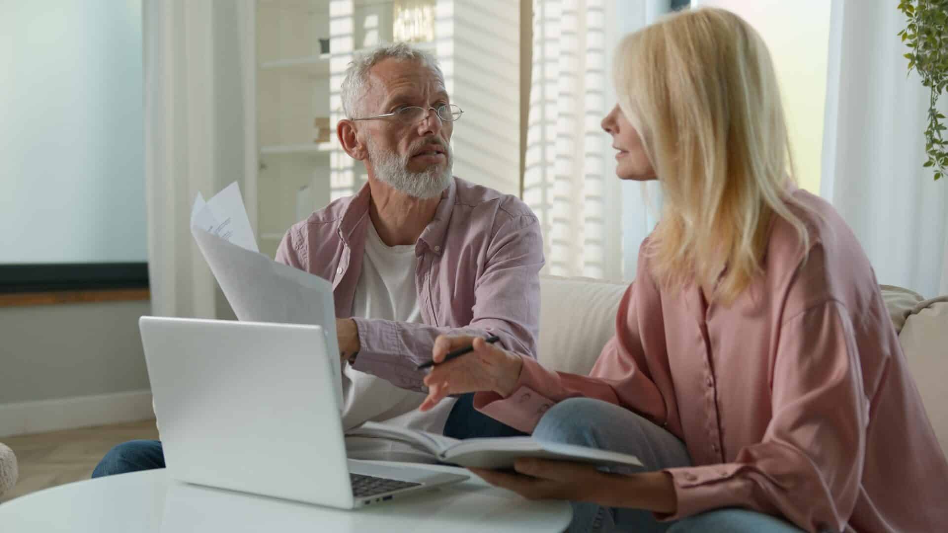 Frustrated old Caucasian couple adult senior woman mature angry man businesspeople argue use bank