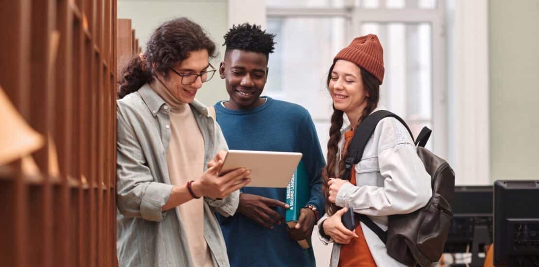 Group of Young People Using Digital Tablet in Library, Canada Caps Study Permits,
