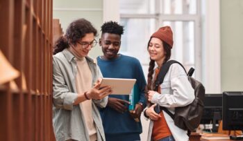 Group of Young People Using Digital Tablet in Library, Canada Caps Study Permits,
