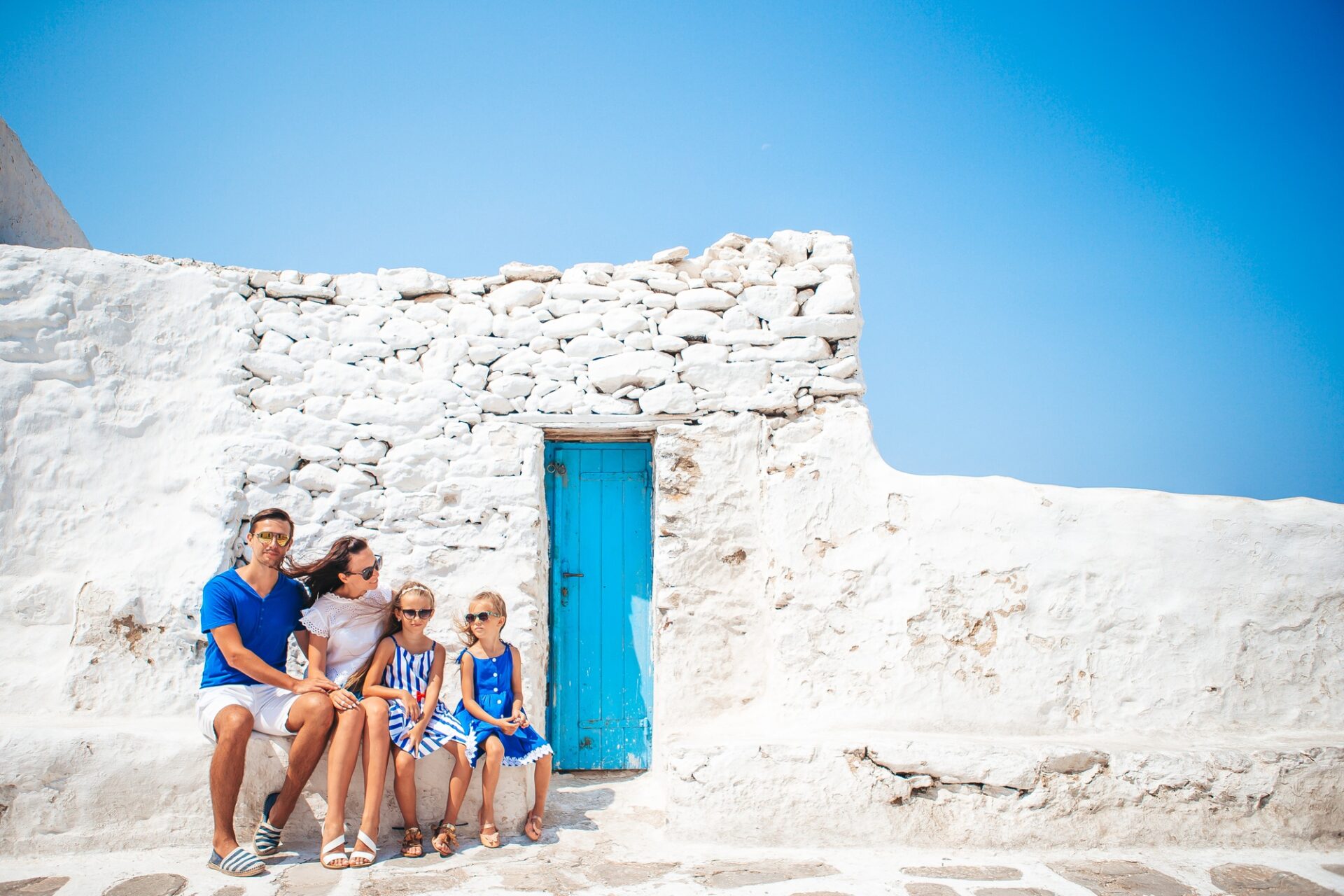 Parents and kids at street of typical greek traditional village on Mykonos Island, in Greece